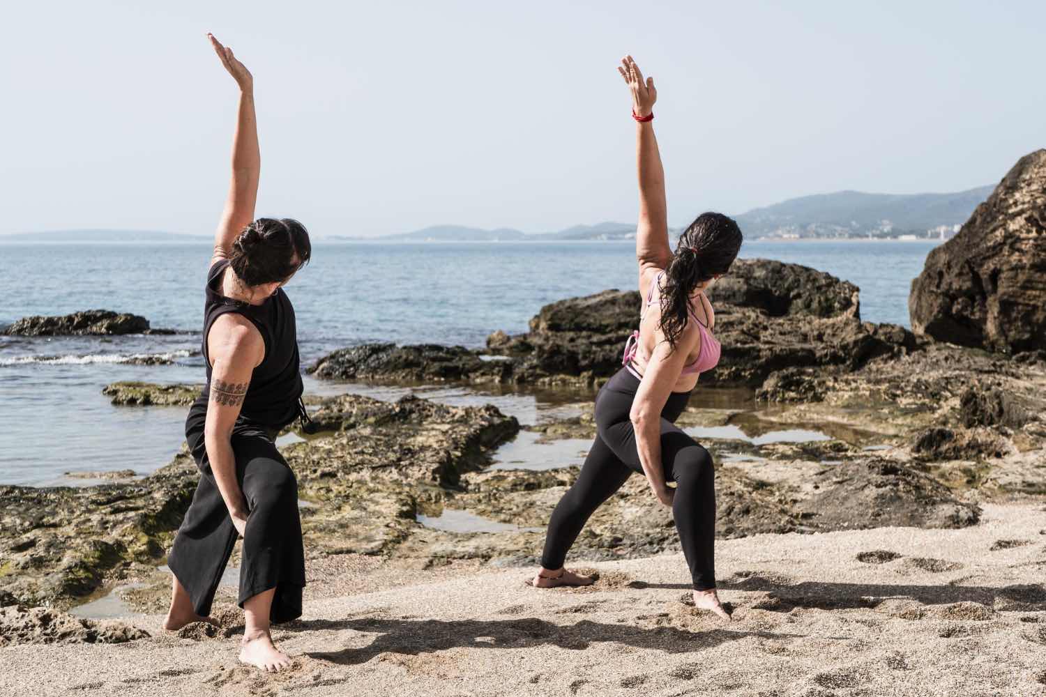 Two people practising yoga on a beach, illustrating how outdoor movement helps manage anxiety on the Sunshine Coast